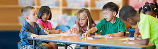 Picture of little kids sitting around a small table talking and coloring.