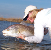 a woman holding a large fish out of the water