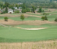 Photo of a golf course with a housing neighborhood in the distance.