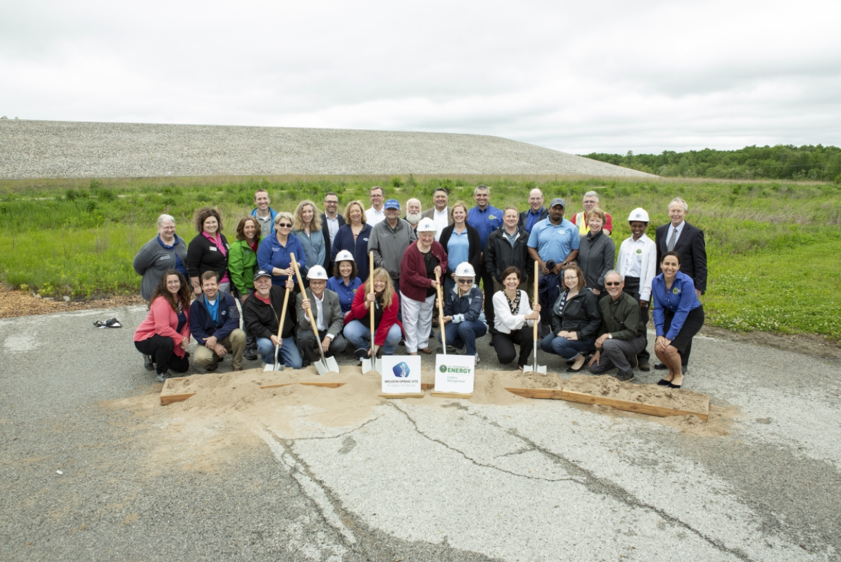 Group of people posing for the camera, several are holding shovels