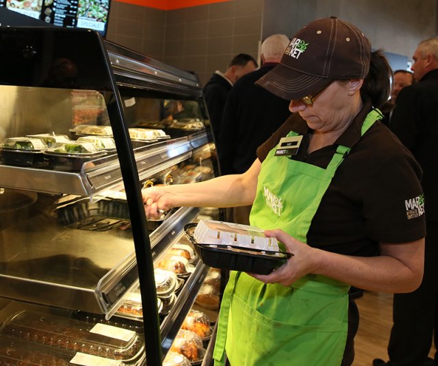 This is a picture of a worker looking at the expiration dates of food in a warming cabinet.