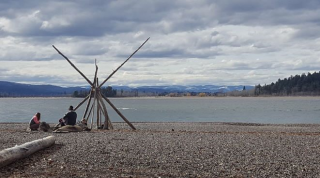 Native Americans sitting on beach at a lake