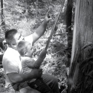 Man and young boy peeling bark from a tree.