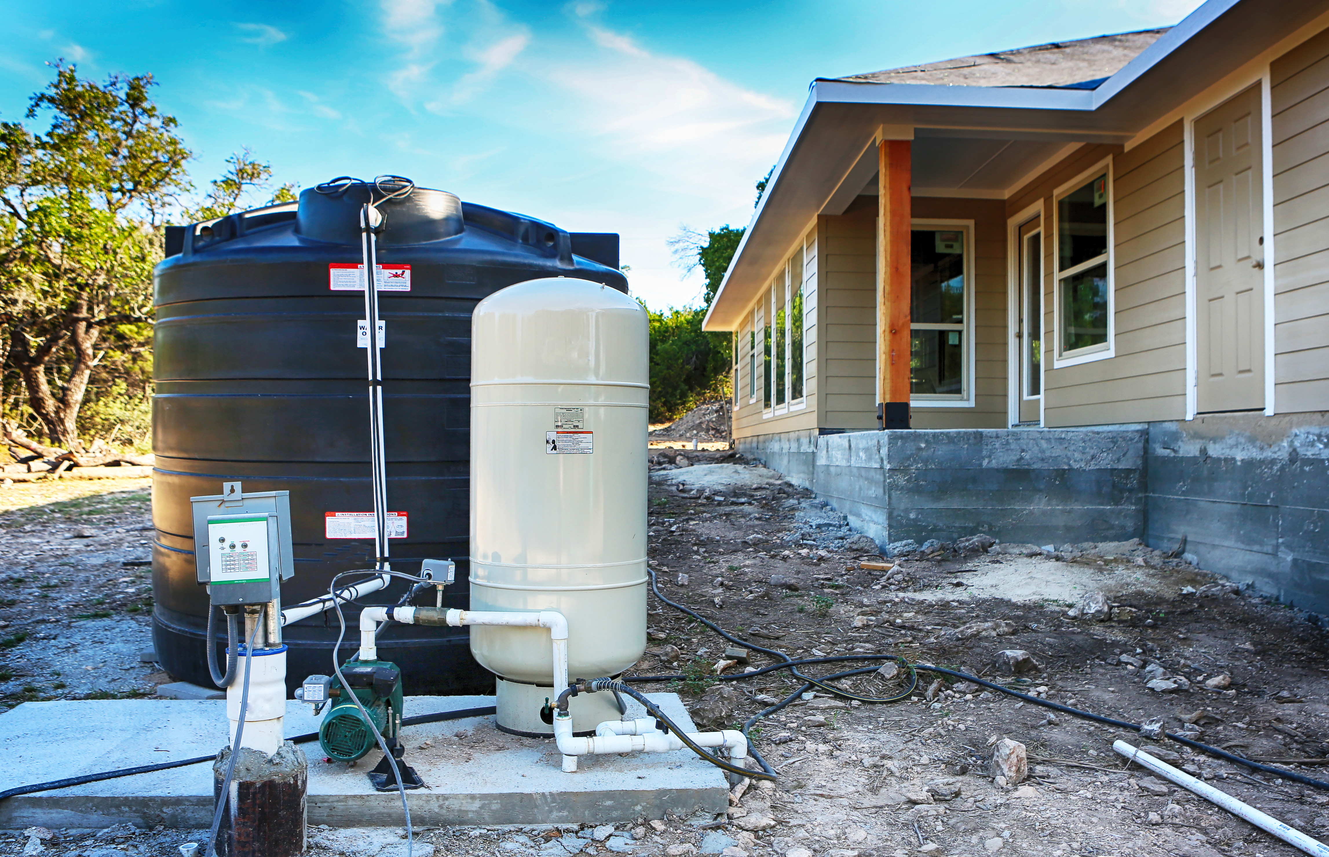 Deep water well set up in front of new home construction.