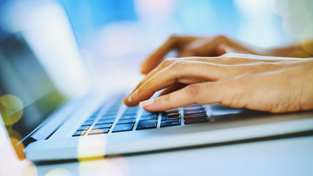 Hands typing on a laptop computer.