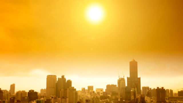 Photo: The sun in a hazy sky over a city.