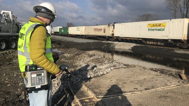 contractor using air monitoring equipment near railroad cars