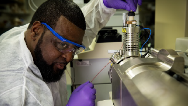 An EPA employee wearing a lab coat, gloves, and protective lenses.