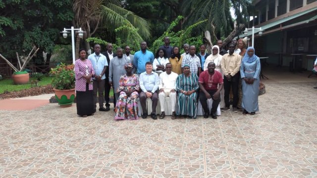 Group photo of participants standing and sitting in front of palm trees who attended the EPIC training in the Gambia. 