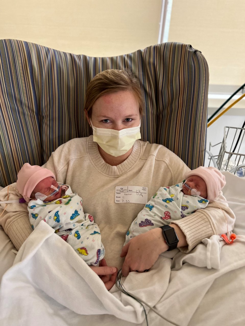 Lauren Duffy sitting in a chair holding her newborn twins