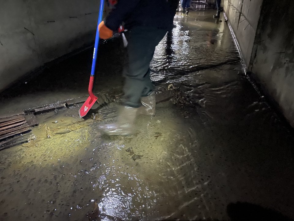 Sediment in a culvert is disturbed to check for sheen