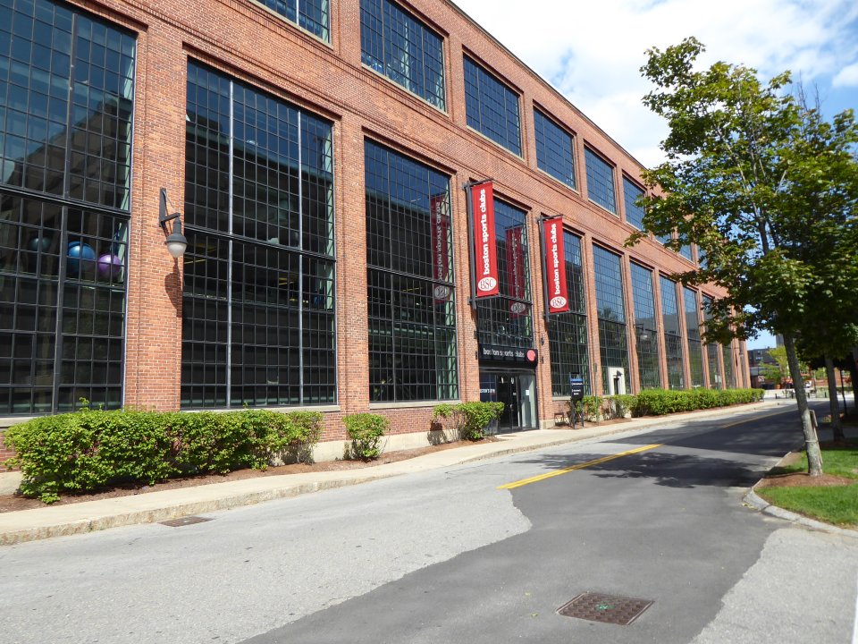 A brick building with large windows with signs saying "boston sports clubs (BSC)"