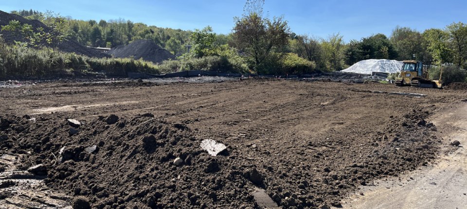 Backfilled soil on one of the tank farm areas with trees in the background.