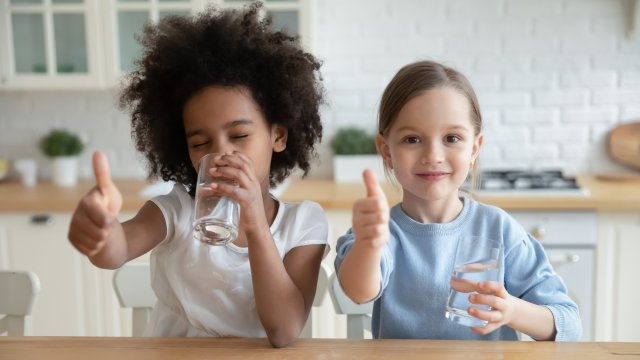 Two girls give thumbs up while drinking water