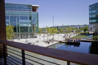 Broad view of the Gates Foundation building with stormwater infrastructure. View features two glass-sided office buildings overlooking a large cement plaza with young trees and two water holding areas.