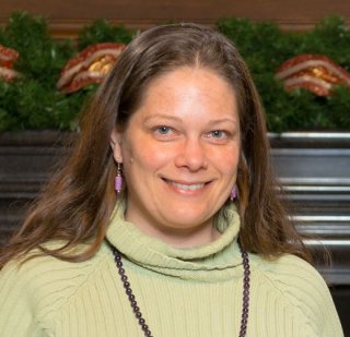 Headshot of a woman with shoulder length brown hair, wearing a light green sweater