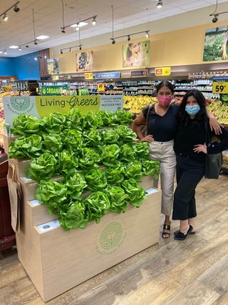 Image of shoppers posing in front of fresh produce. 