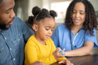 Father with his daughter, while a nurse examines her.