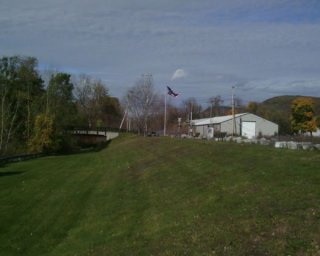 Grassy field with building and bridge in the background