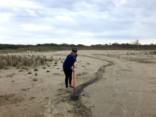 Someone digging a runnel by hand to drain surface water.