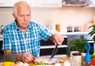 Older adult prepares fish for consumption.