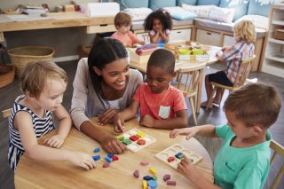 Adult sits with kids at child care