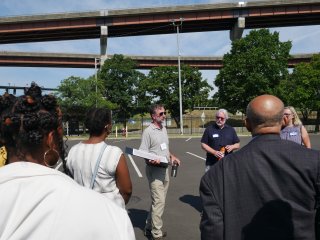 This image shows a group of people talking in front of an elevated highway. 