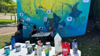 Mural con Consciencia. Artist painting an ocean inspired wall mural including a seal, coral and fish.