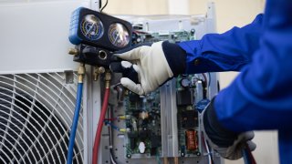 Technician checking refrigerant levels in an air conditioner.