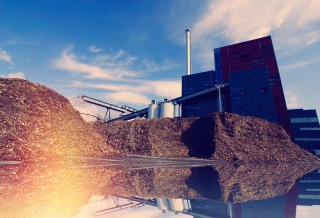 Bio power plant with storage of wooden fuel against blue sky.