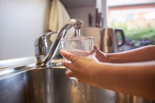 child holding water glass under the faucet