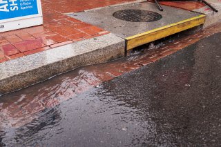 Water flowing along a curb into a storm drain.