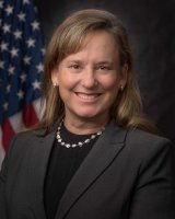 Head and shoulders studio portrait of KC Becker with an American flag in the background