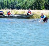 water with two EPA scientists in a boat and one scientist in the water next to the boast with a net in the water.